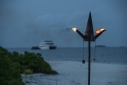 Torches on Meerufenfushi Island with four Seasons Explorer behing