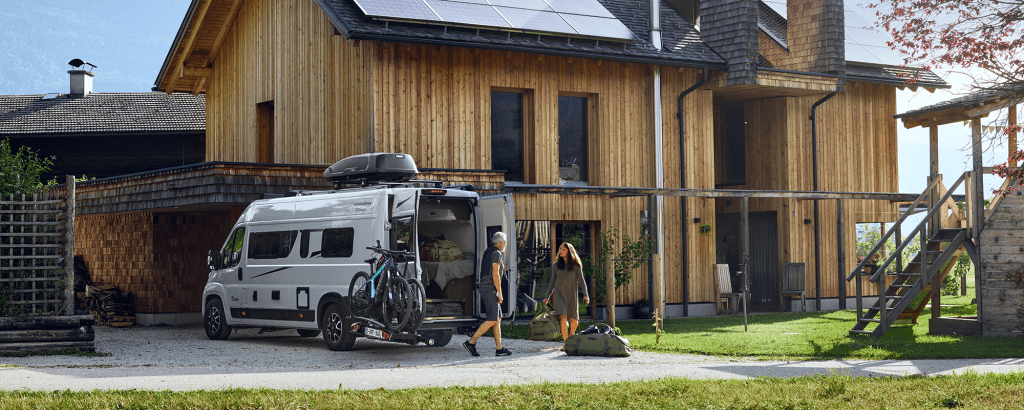 A couple unload gear from their van with e-bikes and a bike rack on the Thule VeloSwing van e-bike carrier.